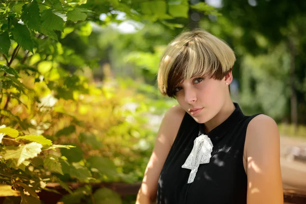 Schöne Mädchen posiert vor einem Hintergrund aus grünem Laub — Stockfoto