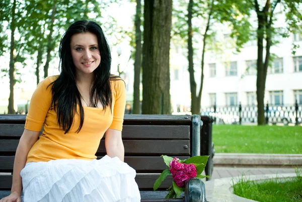 Portrét sladké mladé ženy sedí venku a s úsměvem — Stock fotografie