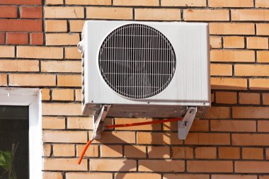 Air conditioning heat pump mounted on brick wall. clipart