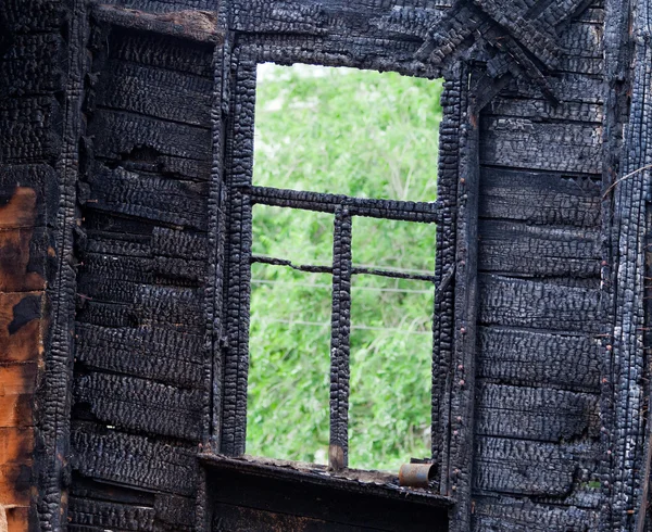 Burned wooden window frame with view to a green trees — Stock Photo, Image
