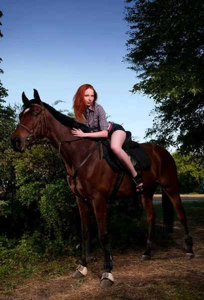 Женщина с рыжими волосами сидит на лошади — стоковое фото