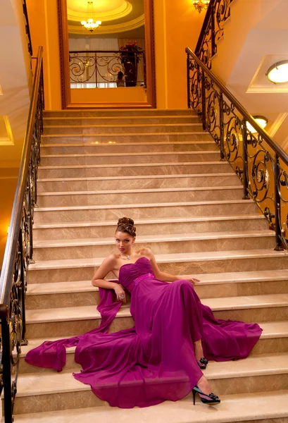 Mulher de vestido comprido deitada nas escadas — Fotografia de Stock