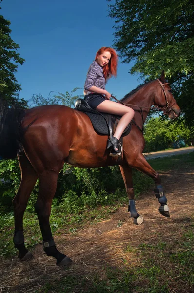 Γυναίκα με τα κόκκινα μαλλιά που κάθεται σε ένα άλογο — Φωτογραφία Αρχείου