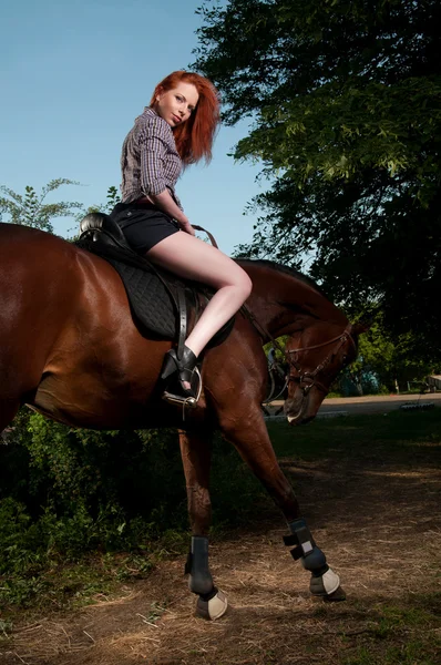 Femme aux cheveux roux assise sur un cheval — Photo