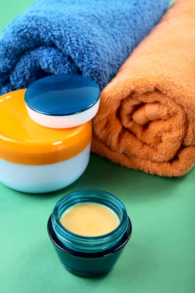 Still-life cosmetic cream and towels on a green — Stock Photo, Image