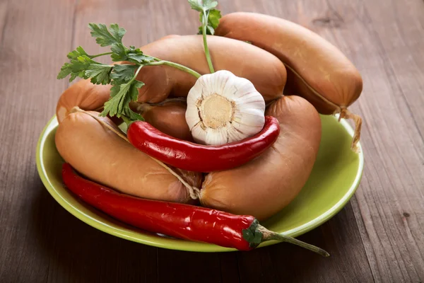 Korv med kryddor och grönsaker på ett träbord — Stockfoto