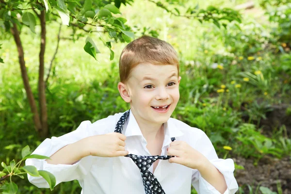 The little boy unties a tie against green — Stock Photo, Image