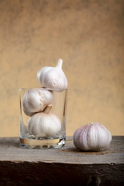 Still-life with garlic and a glass on table — Stock Photo, Image