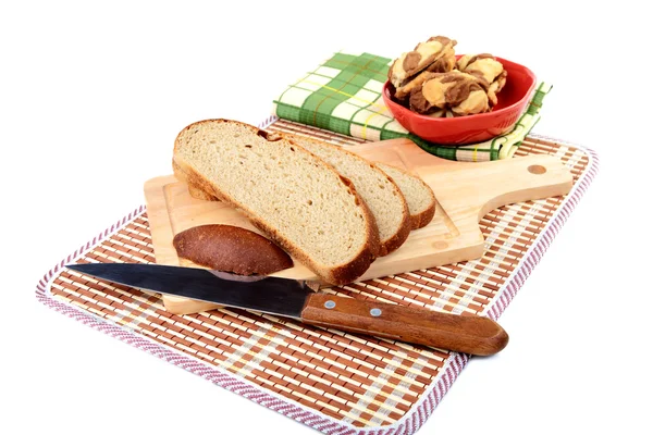 Fatias de pão com faca tábua de cortar e toalha em um branco — Fotografia de Stock
