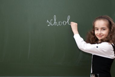 Schoolgirl writes on a blackboard clipart