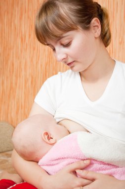 Baby breast feeding in home clipart