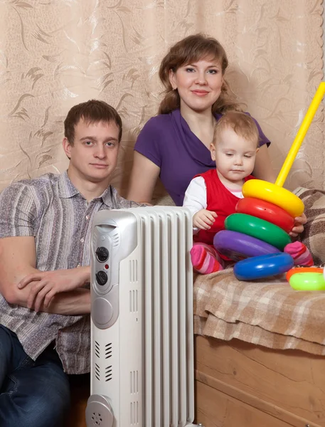 Genitori e bambino vicino al radiatore caldo — Foto Stock
