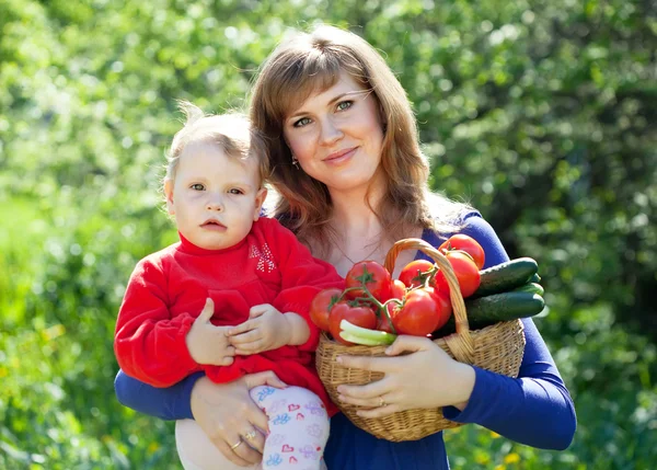 Mulher e bebê com legumes no jardim — Fotografia de Stock