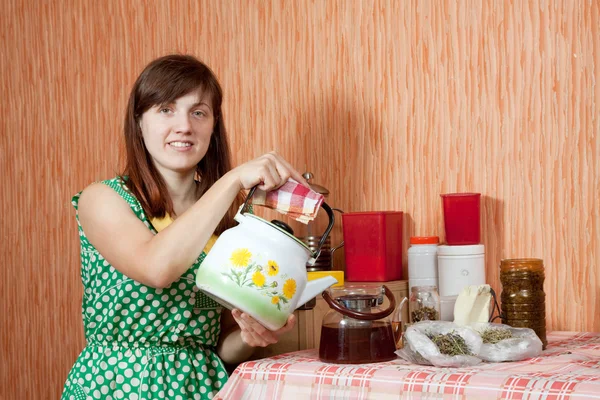 Woman brews herbs in teapot — Stock Photo, Image
