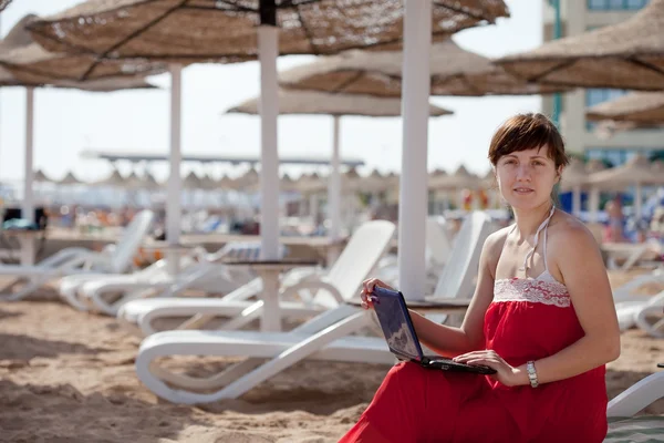 Woman using laptop at resort beach — Stock Photo, Image
