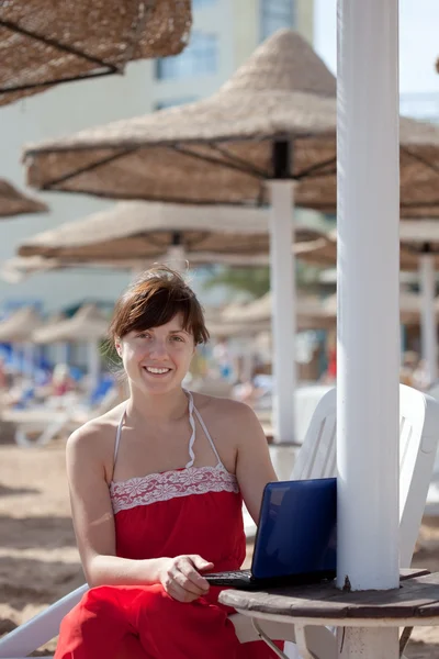 Frau benutzt Laptop am Strand des Resorts — Stockfoto