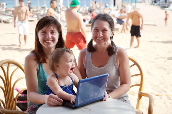 Donne e ragazza con computer portatile in spiaggia — Foto Stock