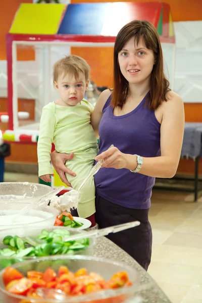 Woman with chid chooses vegetables in buffet — Stock Photo, Image
