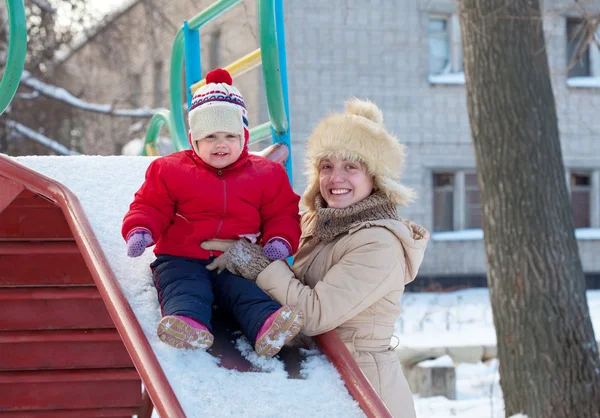 Mutlu anne ile kışın slayt üzerinde yürümeye başlayan çocuk — Stok fotoğraf
