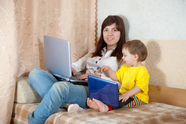 Kobieta z malucha za pomocą laptopów w salonie — Zdjęcie stockowe
