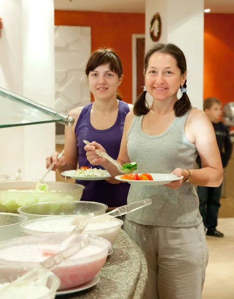Mulheres levam legumes frescos em buffet — Fotografia de Stock