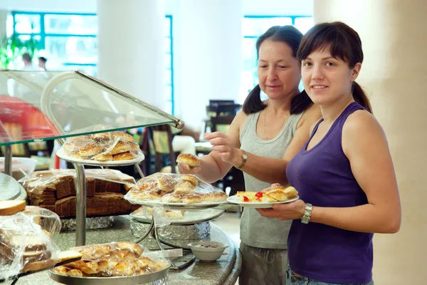 Las mujeres toman pastelería en buffet —  Fotos de Stock
