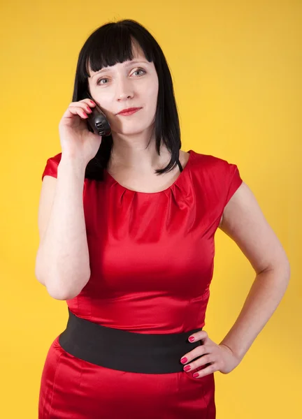 Woman in red speak by phone over yellow — Stock Photo, Image