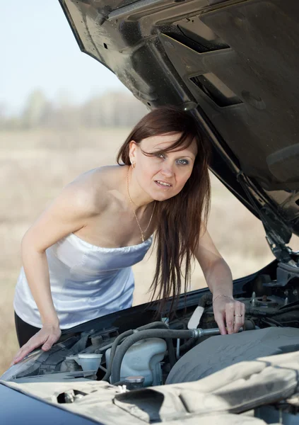 Vrouw op zoek onder auto motorkap — Stockfoto