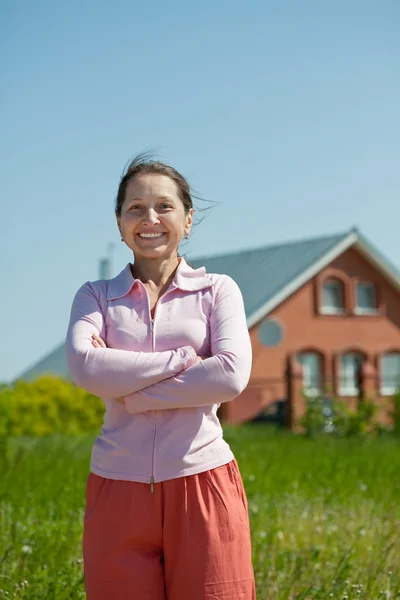 Happy mature woman against her home — Stock Photo, Image