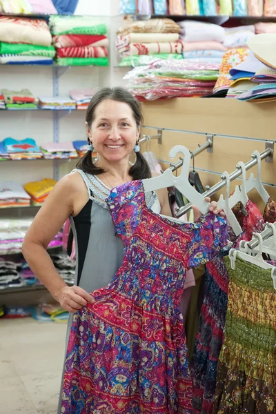 Vrouw kiest jurk bij shop — Stockfoto