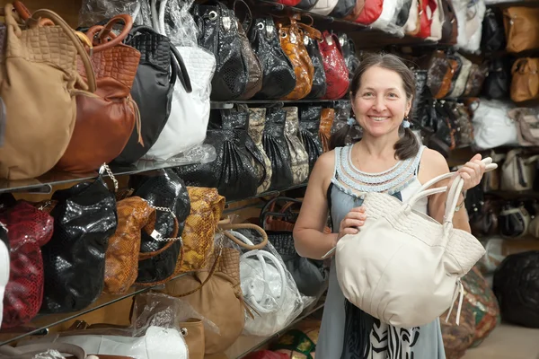 Женщина выбирает кожаную сумку в магазине — стоковое фото