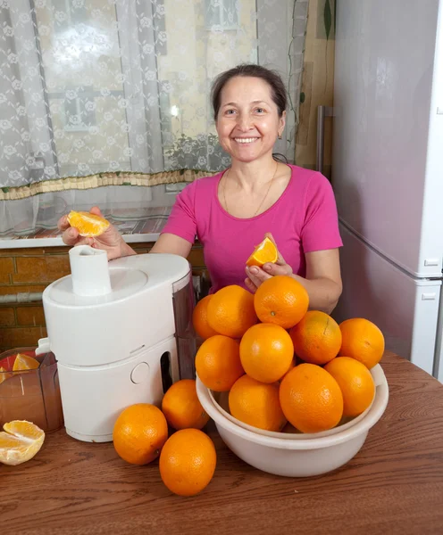 Mulher madura fazendo suco de laranja — Fotografia de Stock