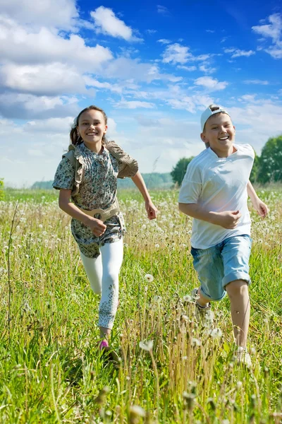 Menino e menina correndo no prado — Fotografia de Stock