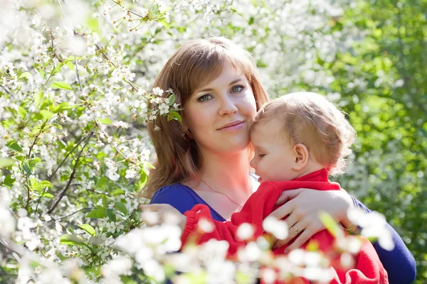 Moeder en baby in bloeiende tuin — Stockfoto