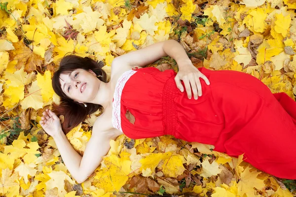 Νεαρή γυναίκα βρίσκεται σε φύλλα σφενδάμου — Φωτογραφία Αρχείου