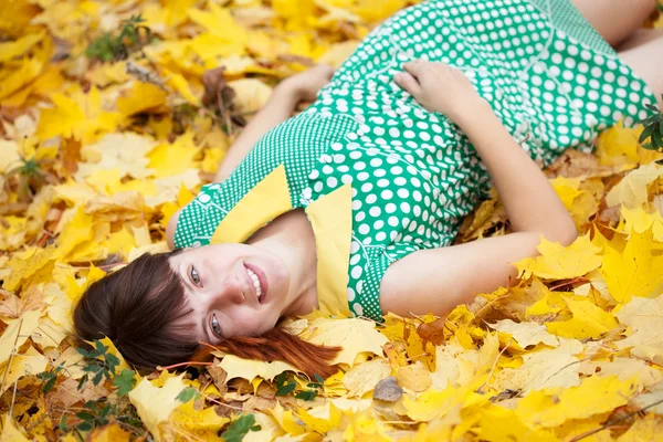 Jonge vrouw ligt in herfst park — Stockfoto