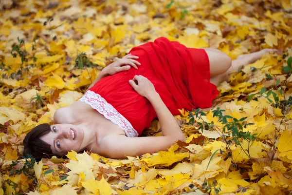 Junge Frau liegt in Ahornblättern — Stockfoto