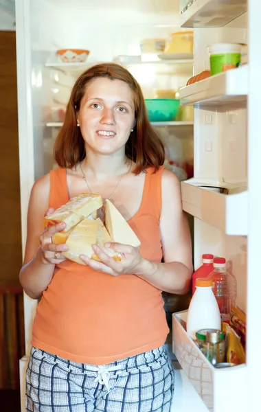 Woman with cheese near refrigerator — Stock Photo, Image