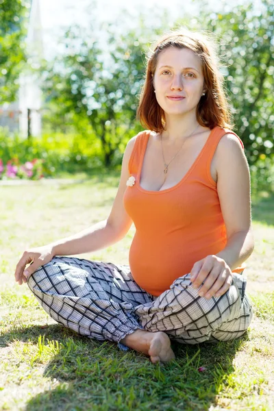 Беременная женщина сидит на траве — стоковое фото