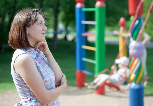 Kobieta zadumy przed plac zabaw dla dzieci — Zdjęcie stockowe