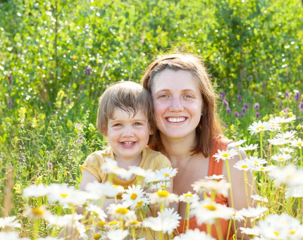 Happy woman with baby in daisy plant — Stock Photo, Image