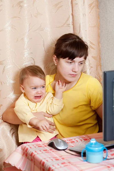 Женщина с плачущим ребенком работает дома — стоковое фото