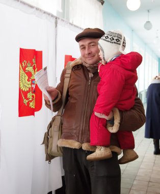 Man with child votes in Russian presidential election clipart