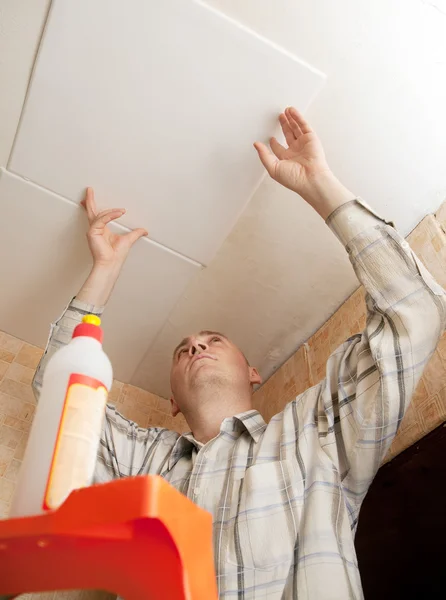 Man glues ceiling tile — Stock Photo, Image