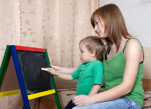 Mor och barn ritar på blackboard — Stockfoto