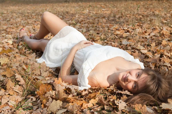 Girl lies in oak leaves — Stock Photo, Image