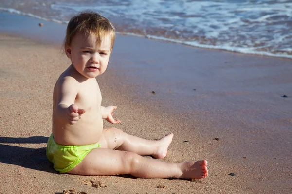 Toddler sits on sand beach — Stock Photo, Image