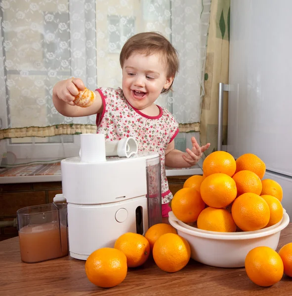 Menina bebê adicionando laranja ao espremedor — Fotografia de Stock