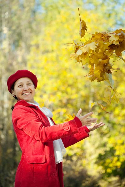Šťastný zralá žena házení javorového listí — Stock fotografie
