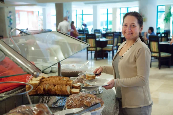 Mature woman chooses sweet pastry — Stock Photo, Image